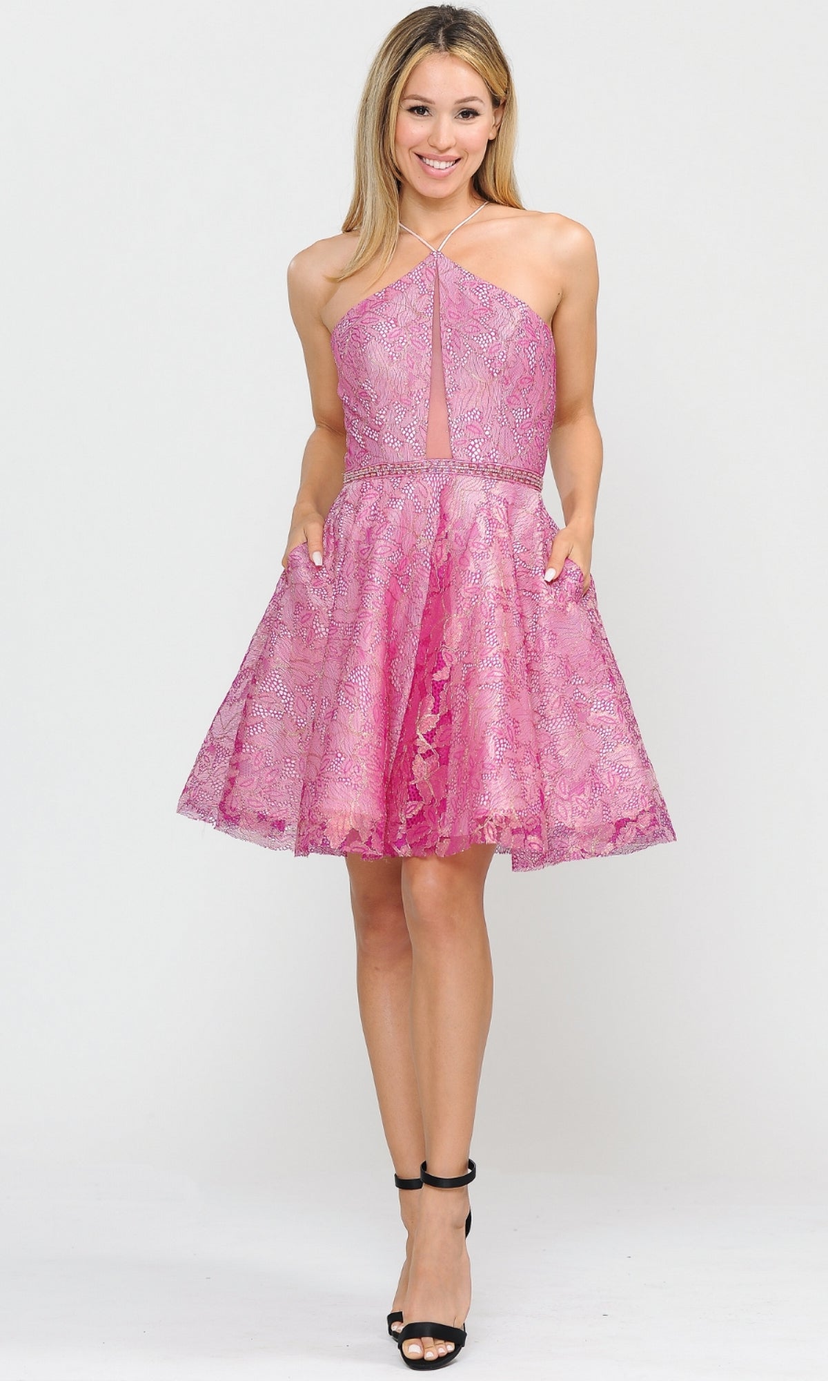 A woman smiles in the Glitter-Mesh Short A-Line Homecoming Dress 8506, featuring a sleeveless halter neckline and paired with black high-heeled sandals, against a plain light background.